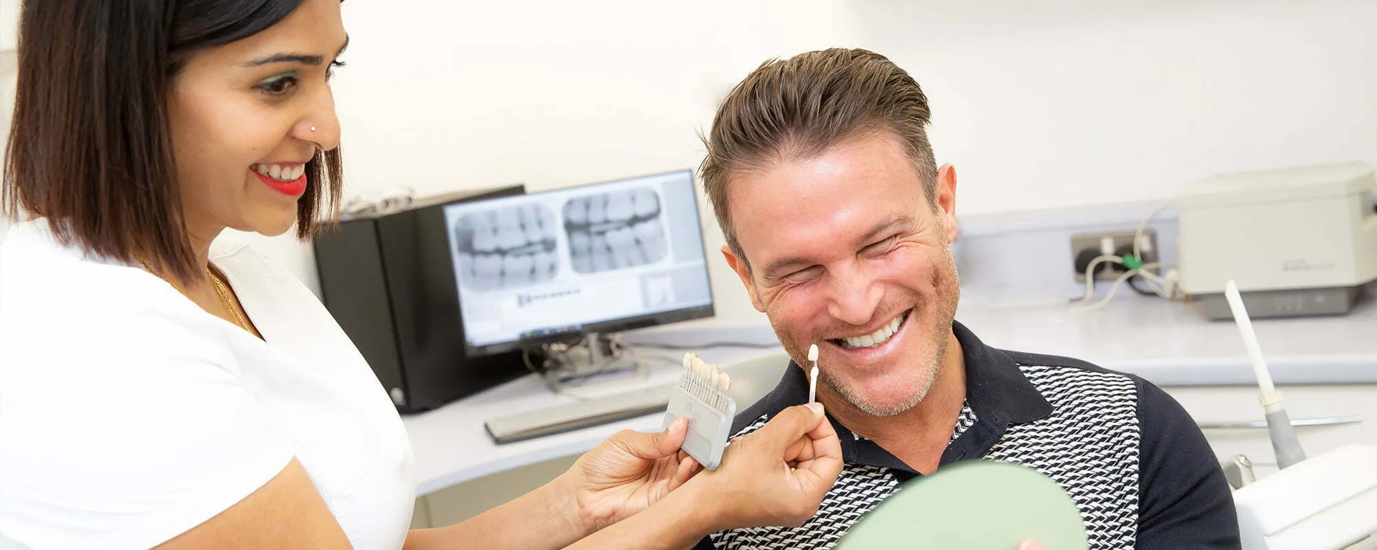 A dentist showing a patient a shade guide during a consultation