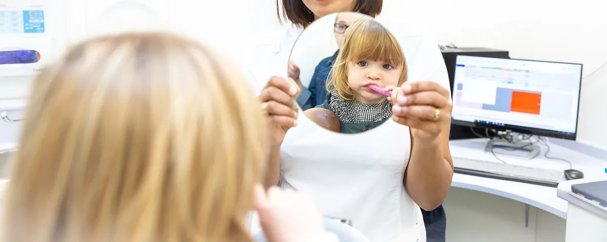 A child brushing their teeth with a dental hygienist