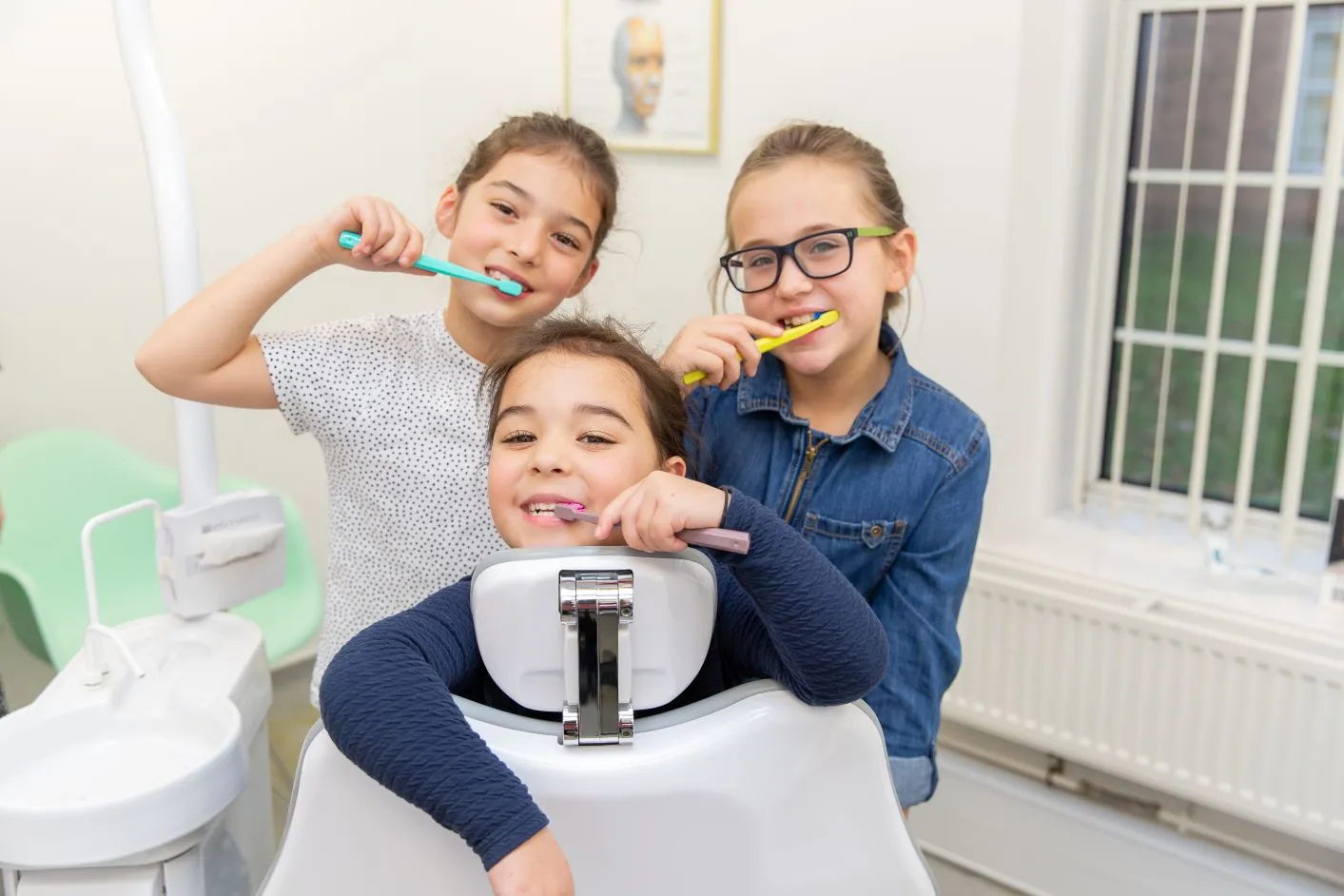 Three children brushing their teeth together at the practice