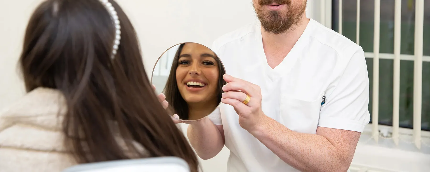 A dentist showing a patient her smile in a hand mirror