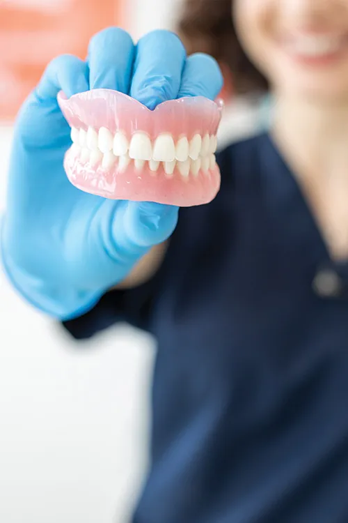 A dental hygienist holding a denture